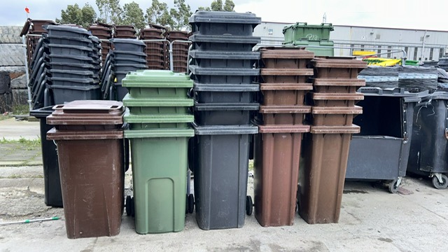 Stacked end-of-life wheelie bins at a recycling yard